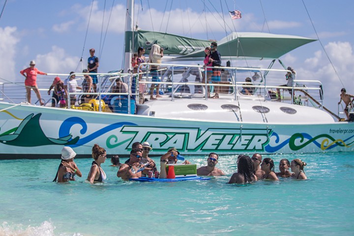 Lunch break on the Traveler catamaran with a few people swimming in front
